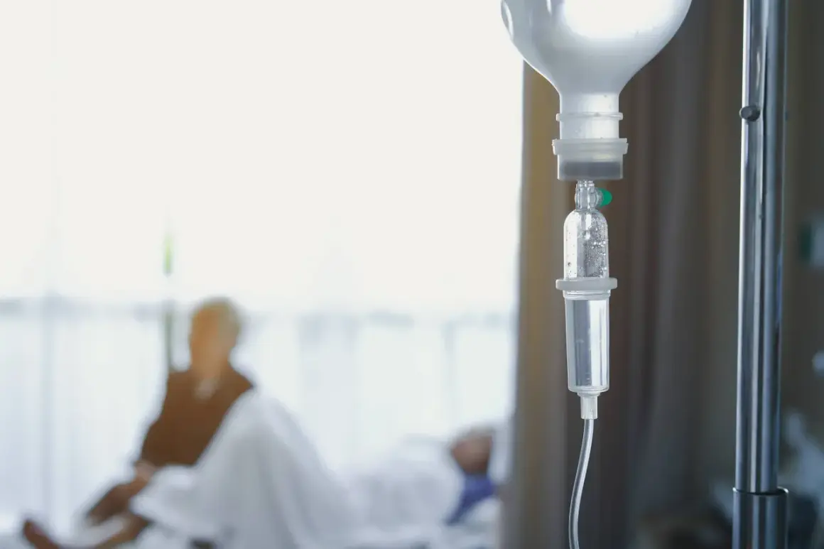 Kroplówka dożylna, symbol nadziei i walki z chorobą. W tle niewyraźna postać pacjenta, który przechodzi chemioterapię.