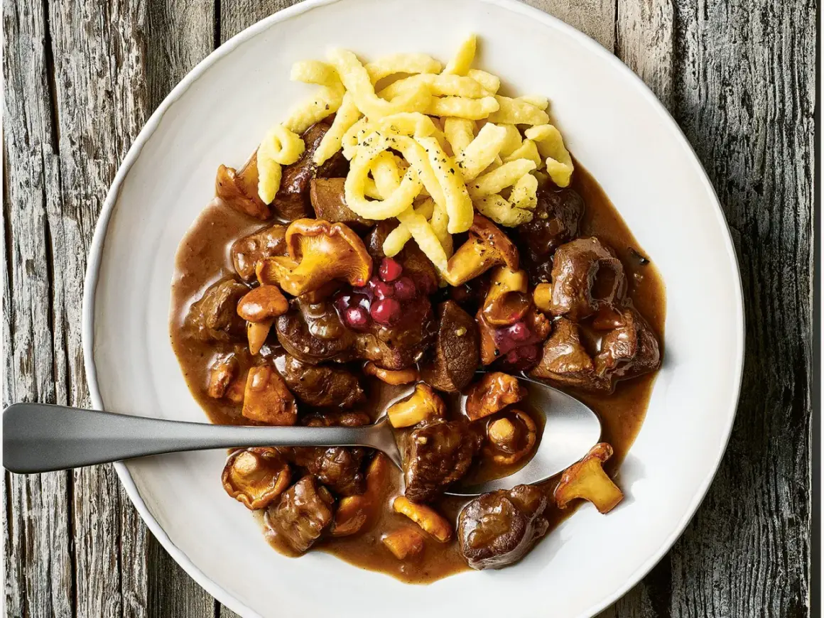 Herzhaftes Rehgulasch mit Rotwein, Pilzen und Preiselbeeren, serviert mit Spätzle. Ein köstliches Rehgulasch Rezept.