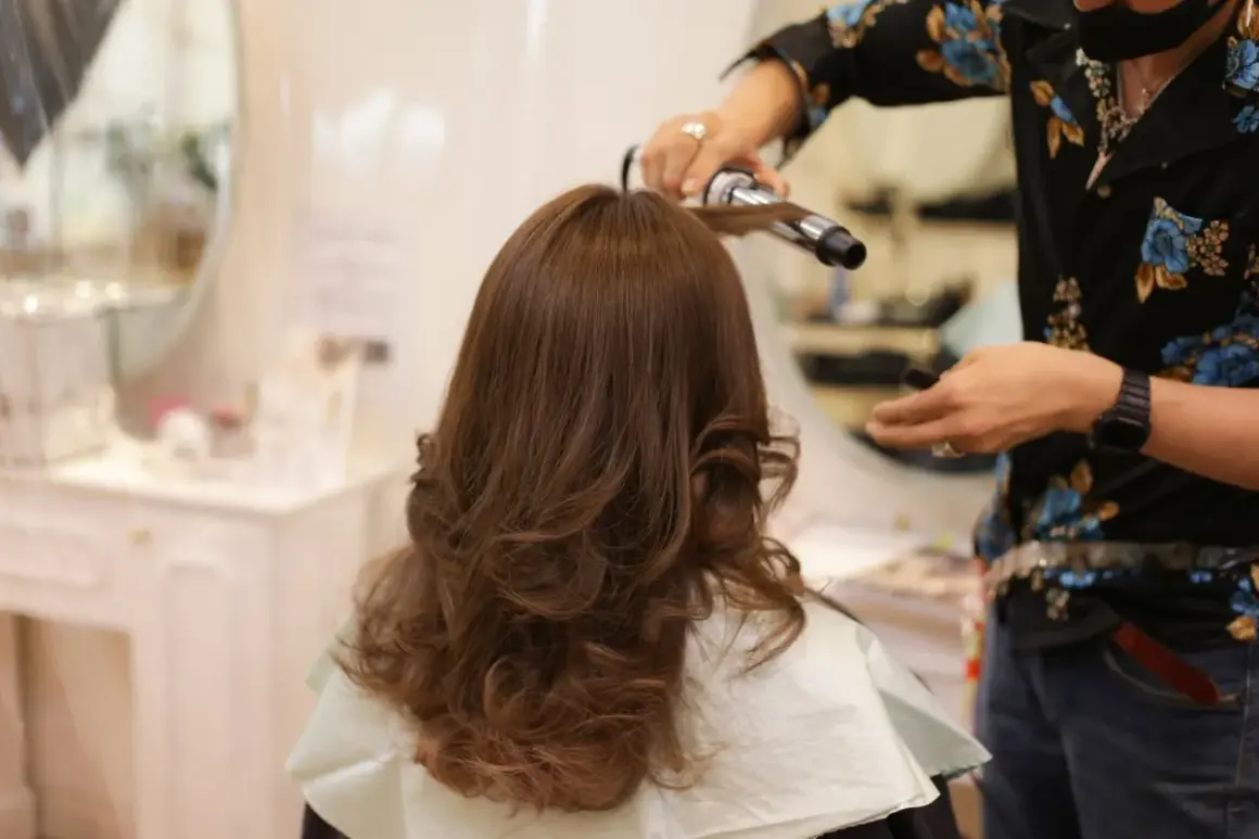 Styling włosów w domu: lokówka tworzy piękne fale na brązowych włosach.
