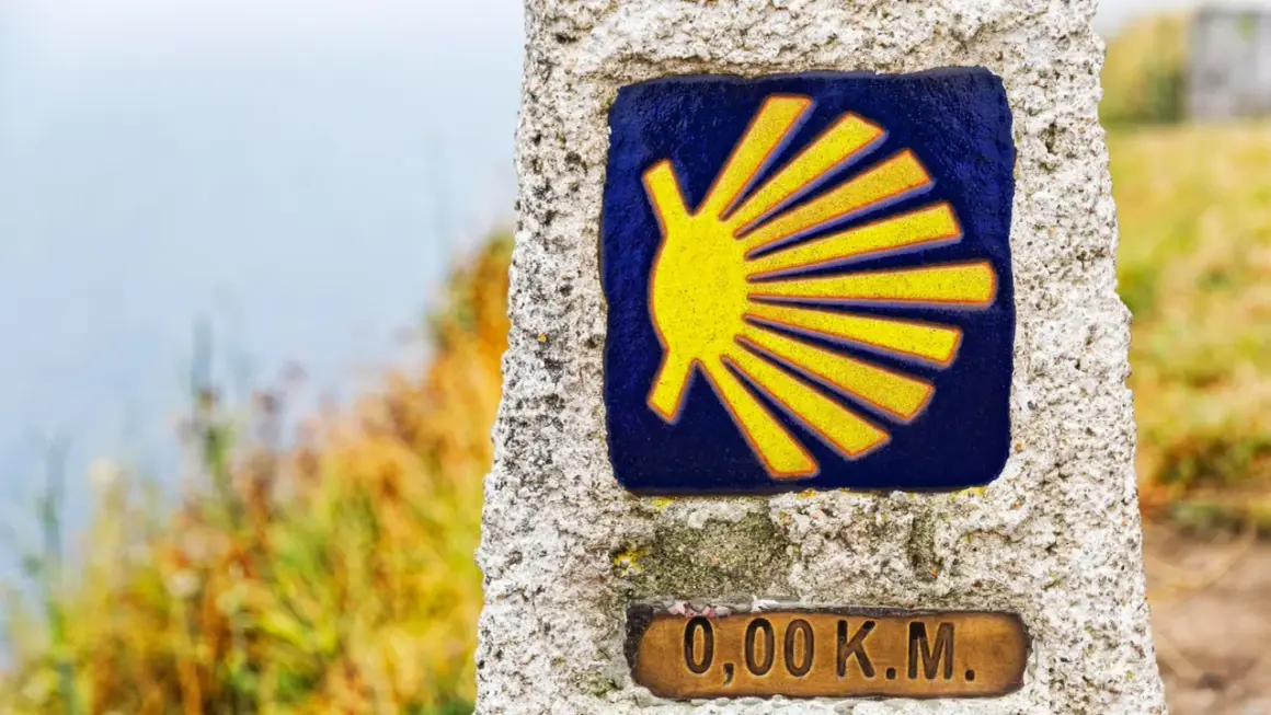 Das Jakobsweg Symbol Bedeutung: Eine gelbe Muschel auf blauem Grund, die den Beginn der Pilgerreise markiert. 0,00 km.
