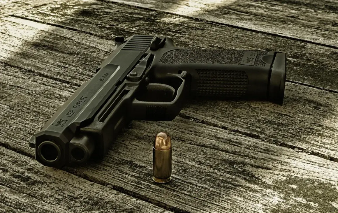 Pistolet HK USP EXPERT kaliber .45 Auto i nabój na drewnianym stole.