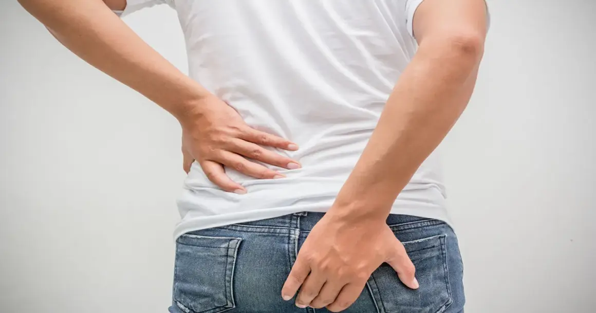 Mann hält sich den Rücken und das Gesäß. Möglicher tumor am after.