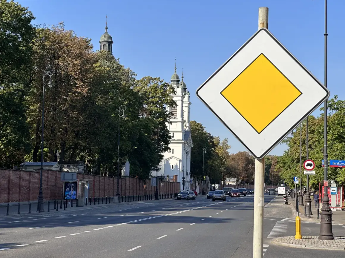 Znak "koniec drogi z pierwszeństwem" na tle kościoła i drzew. Ulica Burakowska w Warszawie.