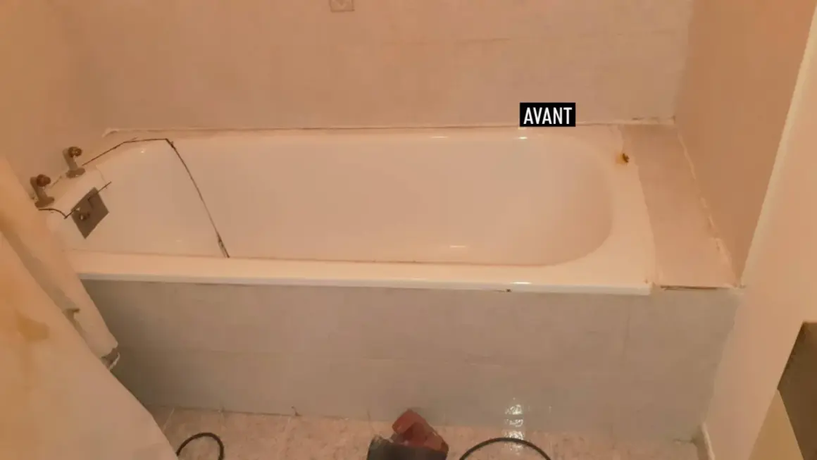 Salle de bain avant rénovation baignoire : baignoire blanche fissurée, robinetterie ancienne, carrelage beige.