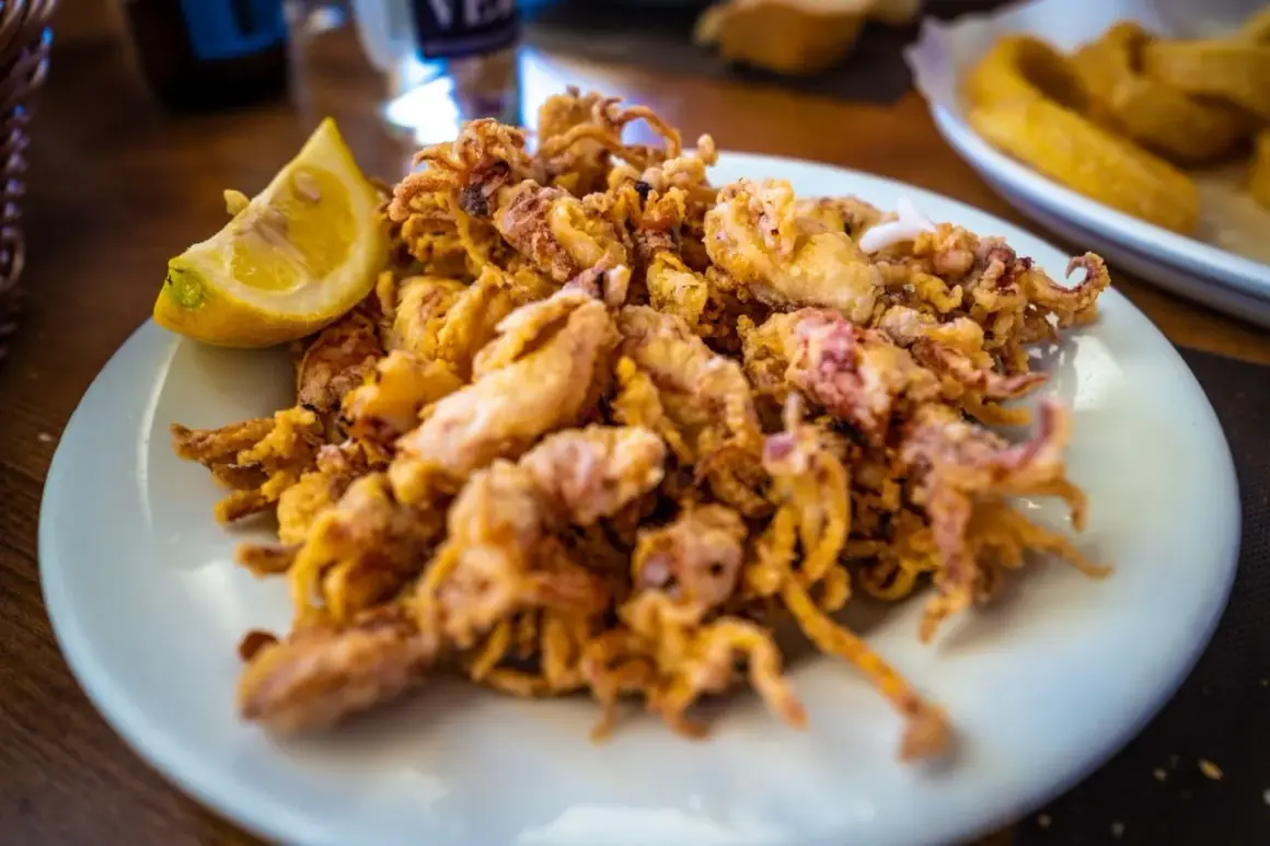 Un plato de puntillas de calamar fritas, doradas y crujientes, con un gajo de limón.