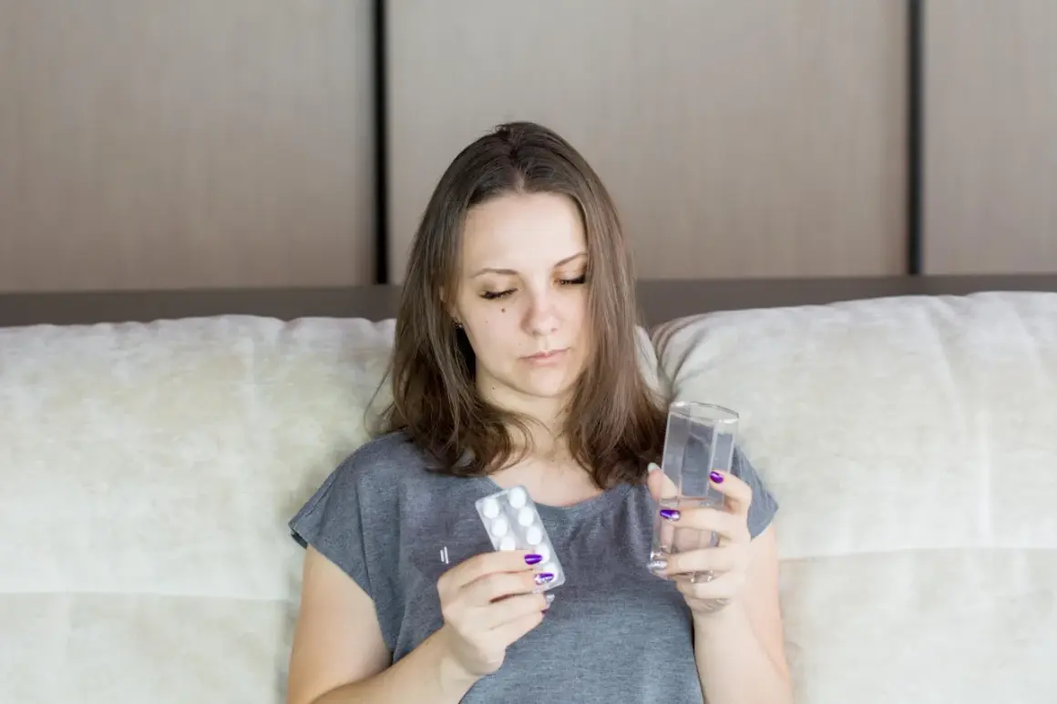 Kobieta zamyślona trzyma tabletki i szklankę wody. Zastanawia się, co to są opioidy i czy powinna je przyjąć.