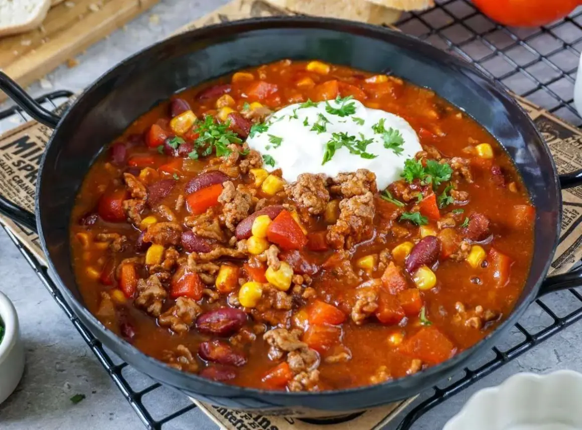 Herzhaftes Chili con Carne Rezept mit Hackfleisch, Kidneybohnen, Mais und Paprika, garniert mit einem Klecks Sour Cream und Petersilie.