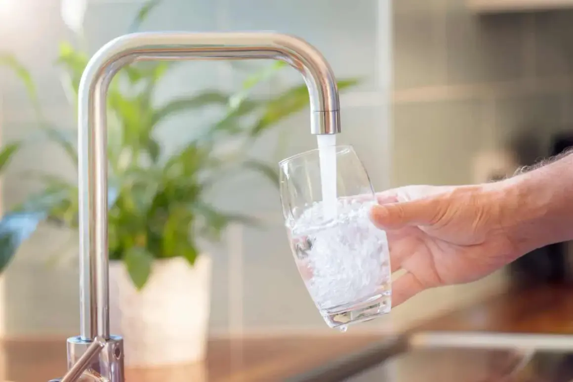 Un robinet verse de l'eau dans un verre, montrant comment obtenir de l'eau filtrée pour une boisson saine.