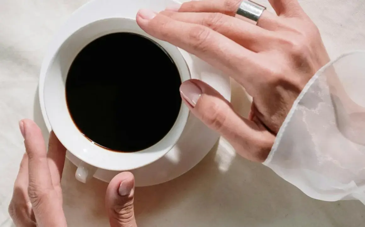 Händer som håller en kopp svart kaffe, en påminnelse om nackdelar med kaffe som sömnlöshet och oro.