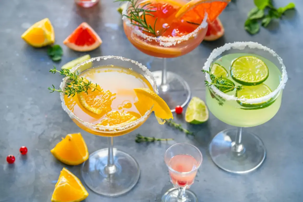 Orzeźwiające drinki z wódką: pomarańczowy, grejpfrutowy i limonkowy, udekorowane owocami i ziołami.