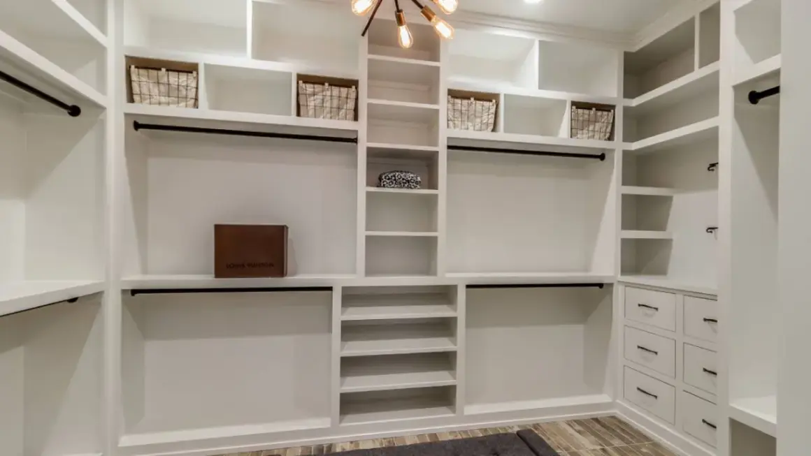 Armario de pladur blanco con cestas, caja de Louis Vuitton y barras para colgar ropa.