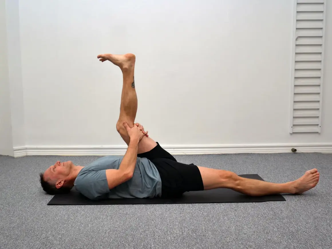 Man utför en leg curl svenska på en yogamatta, sträcker ut ena benet och böjer det andra.