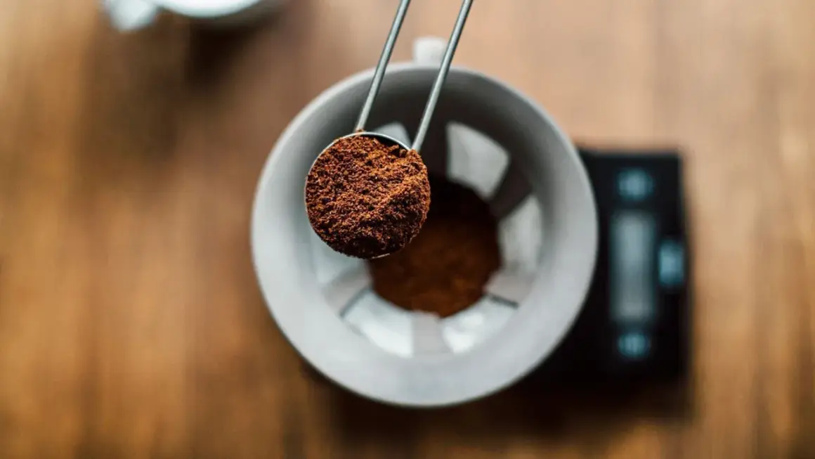 En skopa finmalet kaffe hälls ner i en filterhållare. Perfekt för att mäta rätt mängd gram kaffe per liter vatten för en balanserad bryggning.