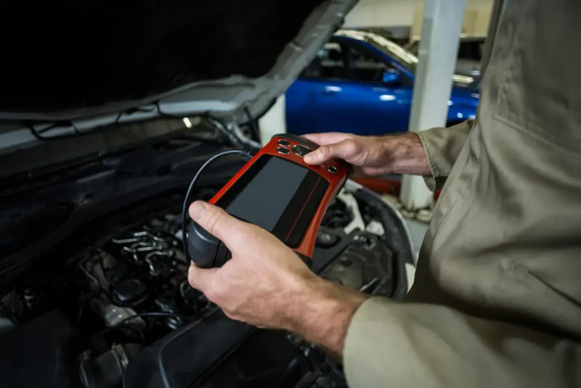 Mechanik z urządzeniem diagnostycznym przy silniku. Czy odłączenie akumulatora na chwilę pomoże zresetować komputer?