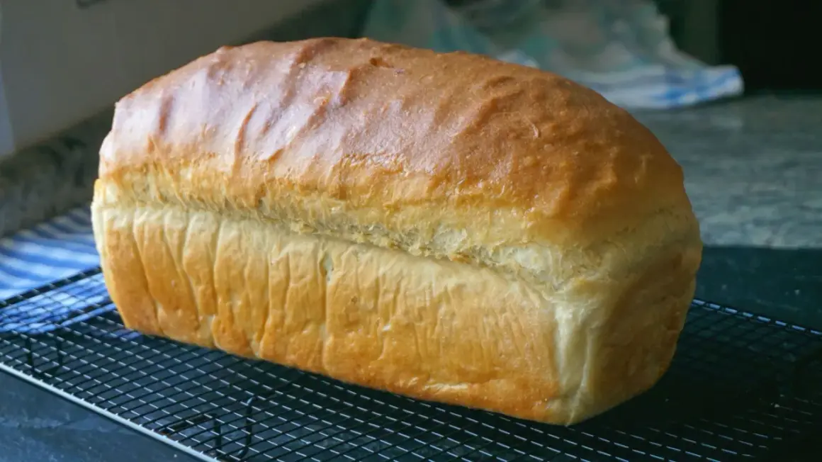 Pan de molde dorado y esponjoso enfriándose en una rejilla, perfecto para tus próximas recetas con pan de molde.