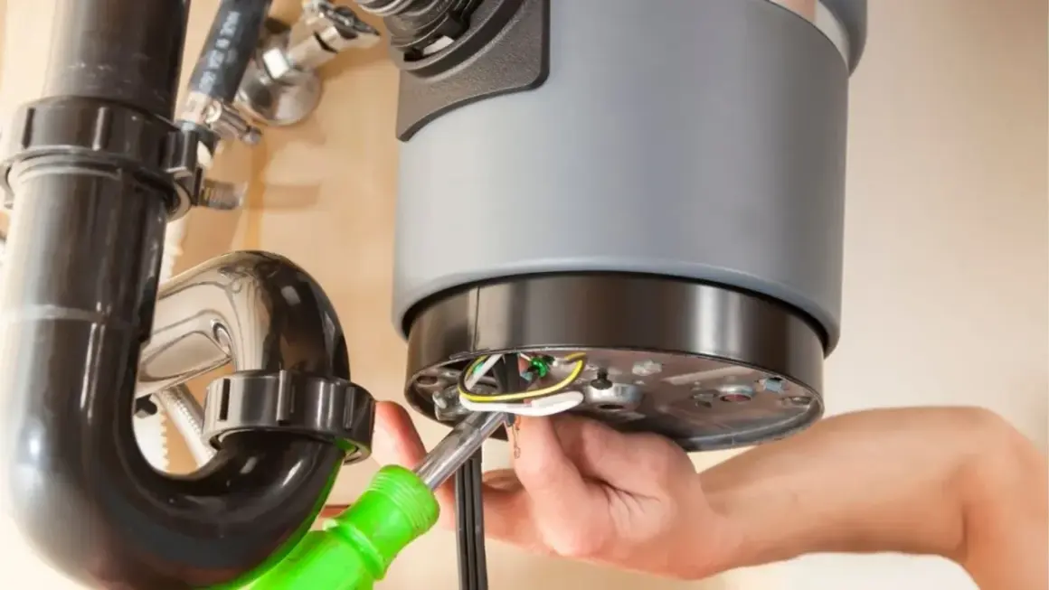 A person is working on a garbage disposal that is not working, connecting wires with a screwdriver.