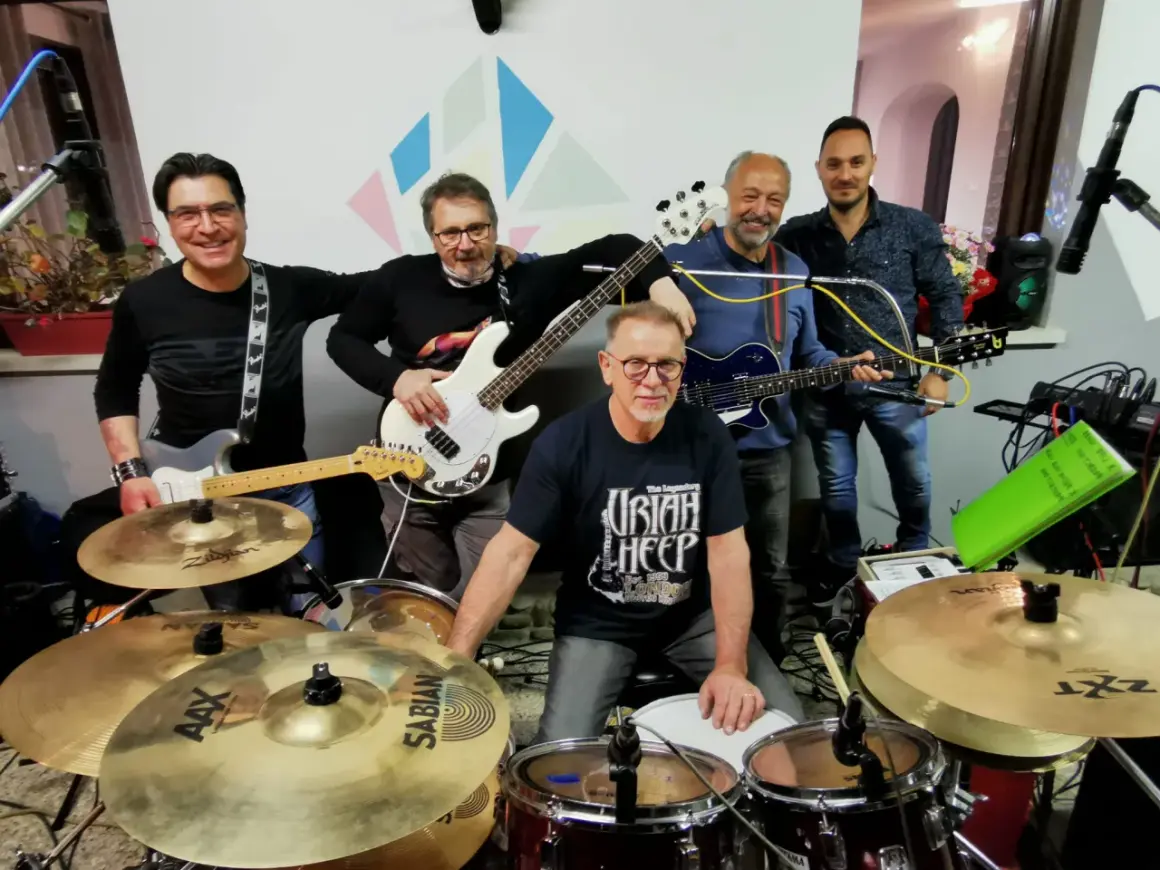 Cinque musicisti sorridenti con chitarre e batteria, pronti a suonare. Potrebbero essere tra i prossimi gruppi musicali veneti famosi.