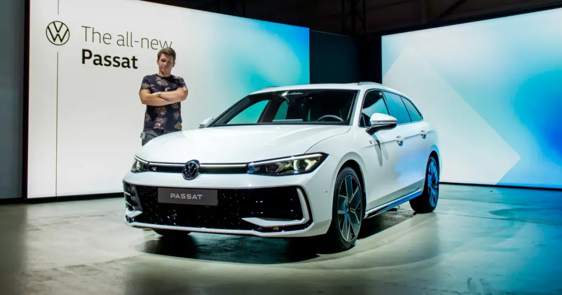 Mężczyzna stoi obok białego kombi, prezentując nowy model Passat B9.
