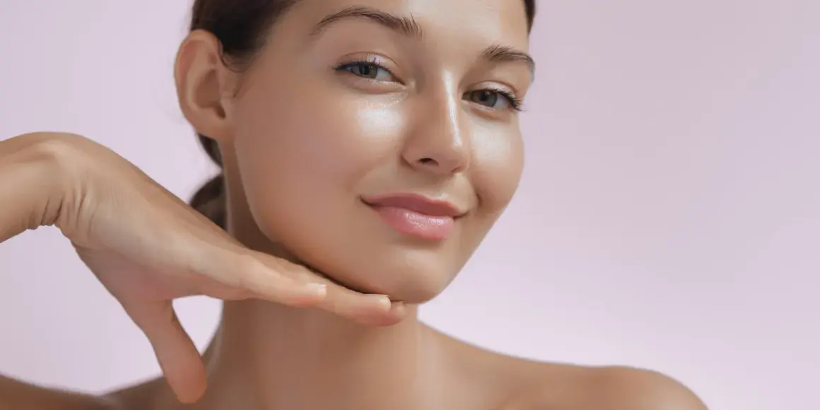 Strahlendes Gesicht einer Frau, die ihr Kinn berührt. Die Haut wirkt glatt und jugendlich, ein Zeichen für die positive retinol wirkung.