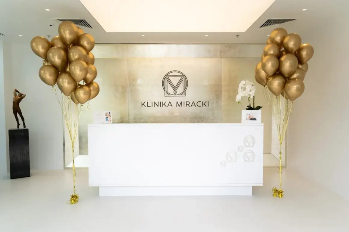 Recepcja kliniki estetycznej z bukietami złotych balonów i rzeźbą.