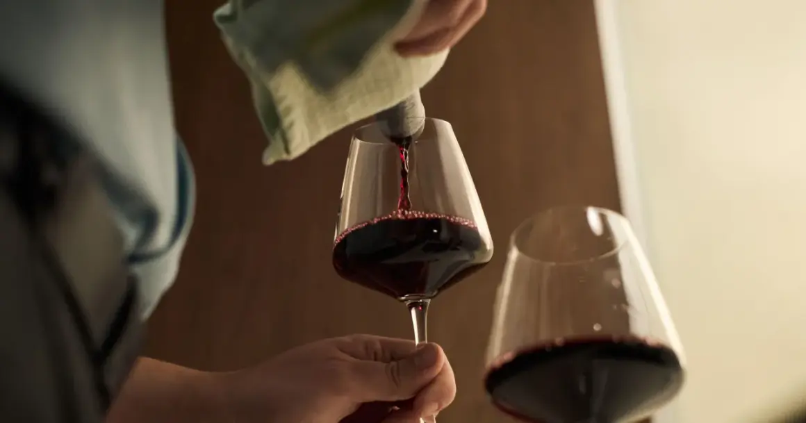 Czerwone wino nalewane do kieliszka. Czy wino jest zdrowe? Debata trwa, ale kieliszek w dłoni wygląda kusząco.