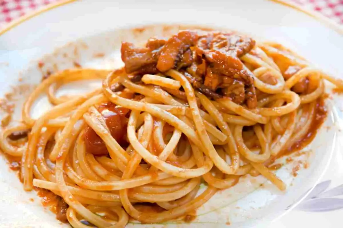 Spaghetti alla chitarra conditi con un ricco sugo di carne e pomodoro, un piatto invitante e saporito.