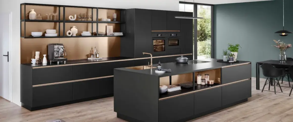 Cocina moderna con isla central, gabinetes negros, detalles dorados y electrodomésticos integrados.