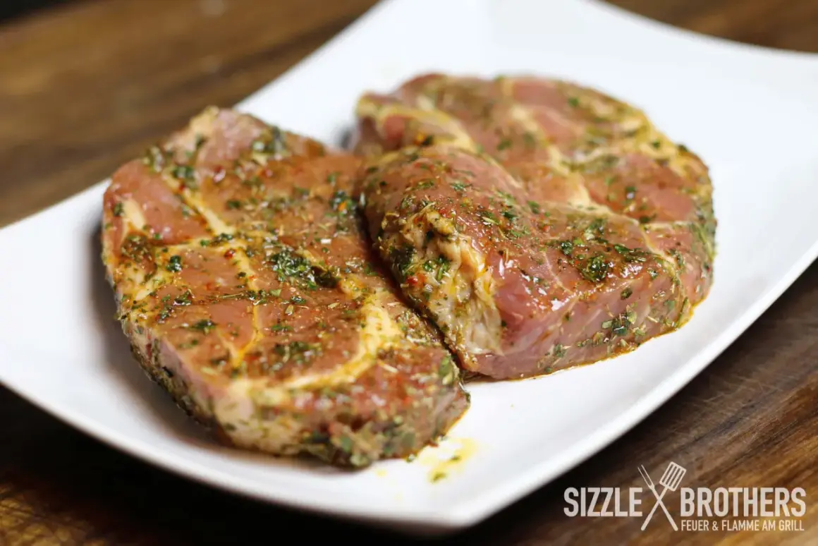 Zwei saftige Steaks, mariniert mit Kräutern und Gewürzen, liegen auf einem weißen Teller. Die Frage: Steak marinieren oder nicht?