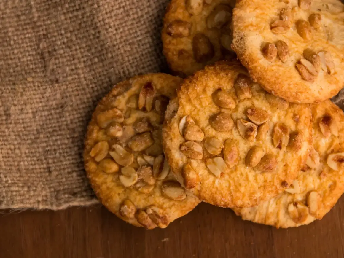 Knusprige erdnuss schoko cookies, verlockend auf Jute und Holz arrangiert.