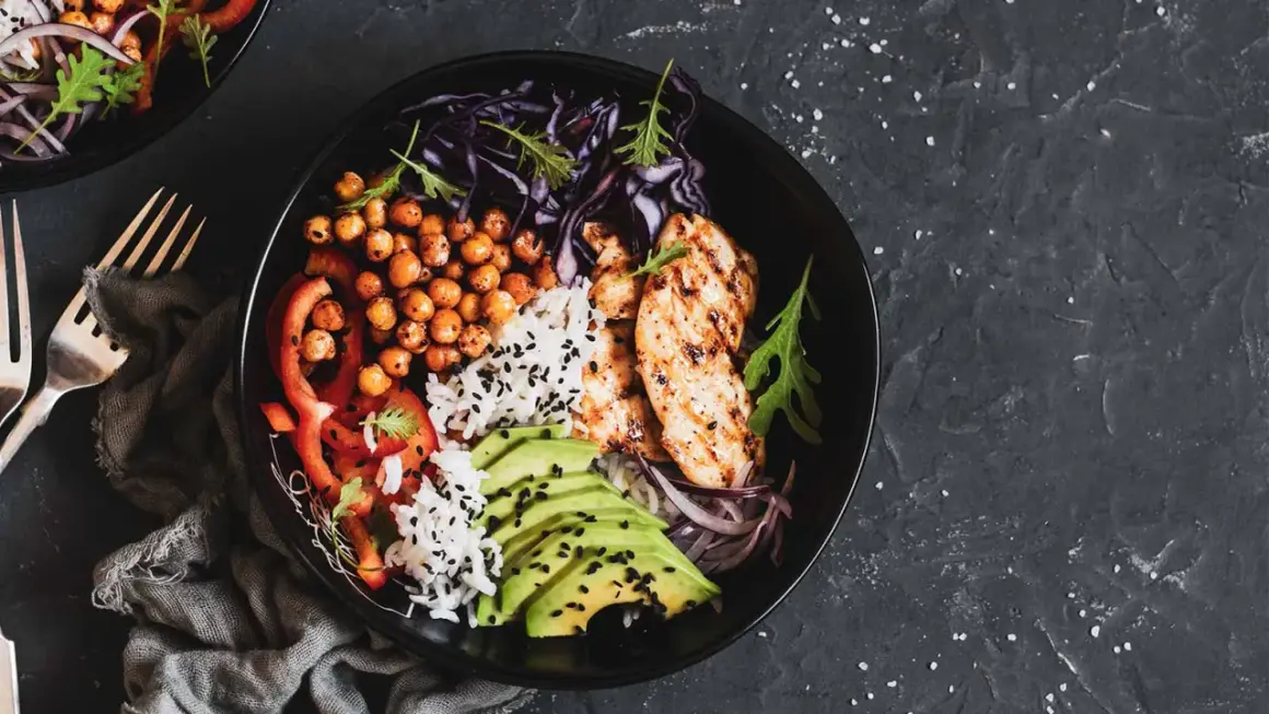 Un bol savoureux avec poulet grillé, riz, pois chiches, avocat et légumes. Parfait pour l'alimentation musculation.