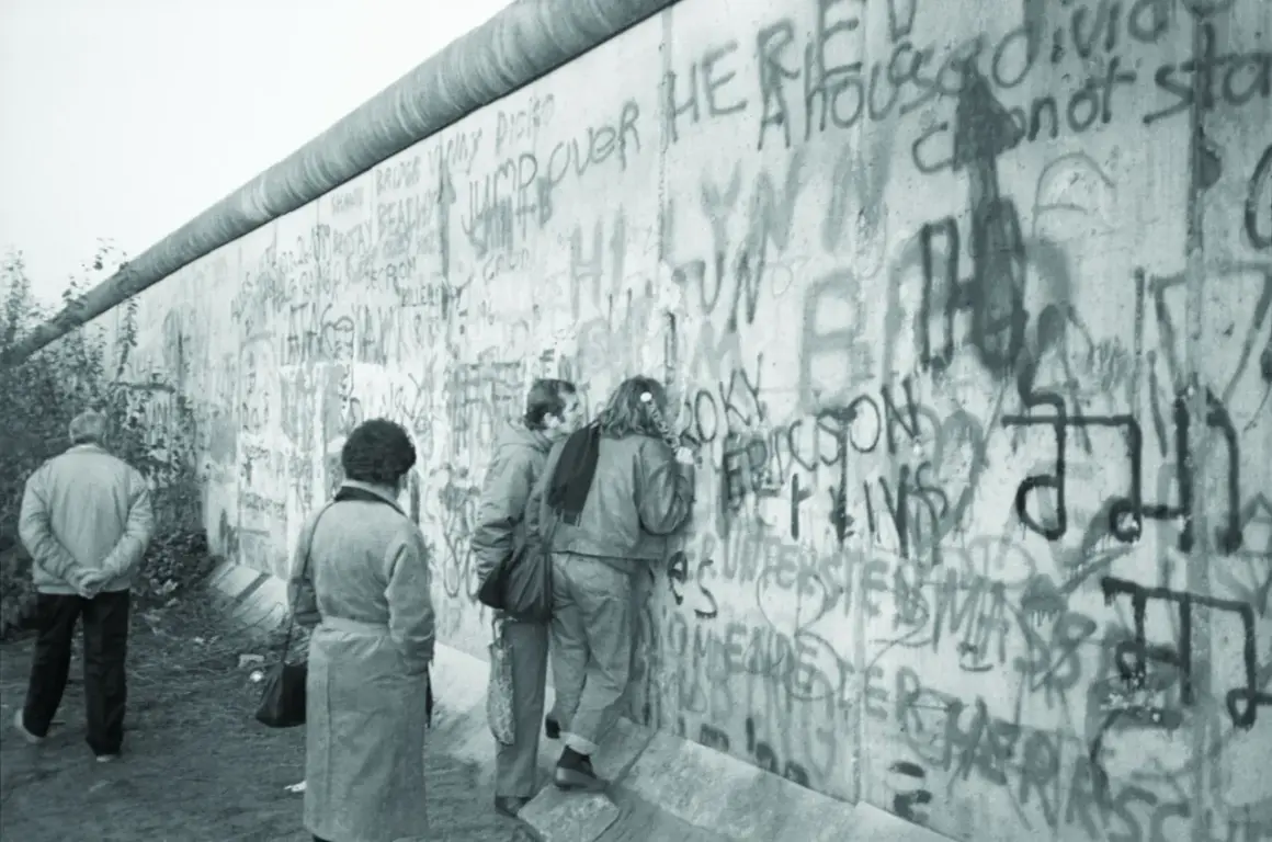 Ludzie oglądają napisy na Murze Berlińskim, gdy upadł mur.