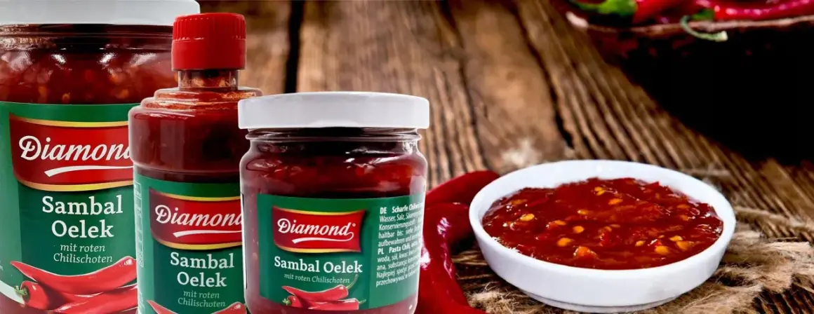 Słoiki z pikantnym sosem Sambal Oelek, z widocznymi papryczkami chili. Idealny do potraw, które potrzebują odrobiny ostrości.