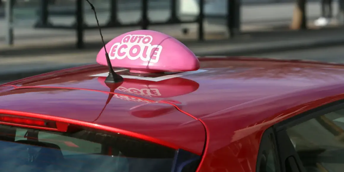 Voiture rouge d'auto-école, prête pour un jeune conducteur responsable qui vise le permis à 17 ans.
