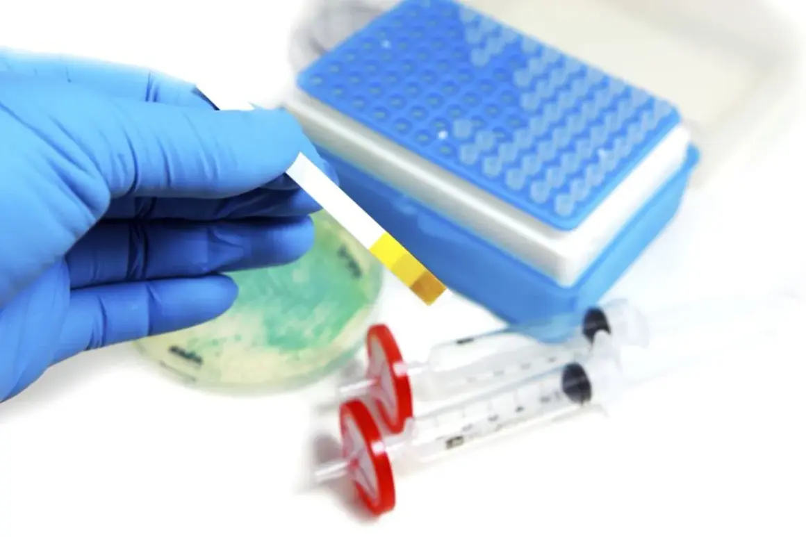 Rękawiczka trzyma pasek testowy, który może pomóc w diagnozowaniu kwasicy mleczanowej. W tle widać sprzęt laboratoryjny.