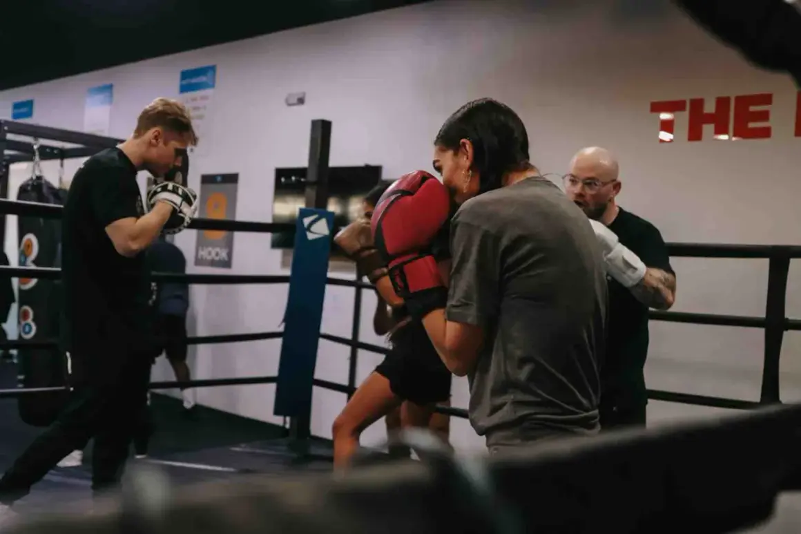Intense soviet boxing training session in a ring. A coach observes as two boxers spar, their gloves a blur of motion.