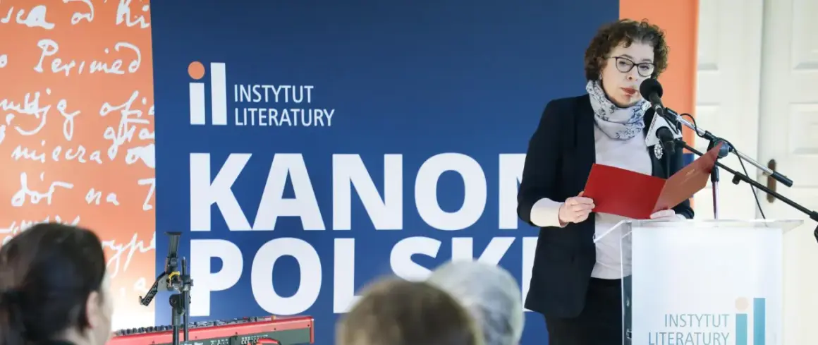 Kobieta przemawia na tle napisu "Instytut Literatury" i "Kanony Polskie", prezentując dzieła najwybitniejszych polskich pisarzy.