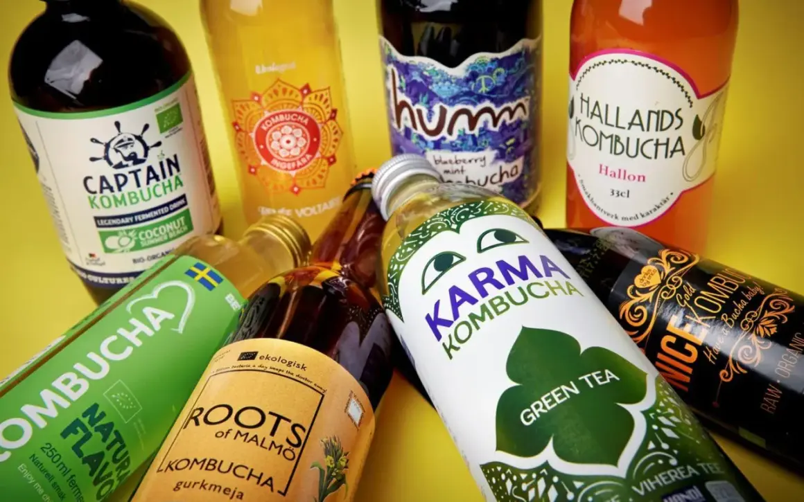 Flera flaskor kombucha, en dryck som många anser vara nyttig, ligger utspridda. Olika märken som Captain Kombucha, Karma Kombucha och Hallands Kombucha syns tydligt.