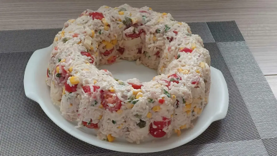 Salade de riz en forme de couronne, garnie de tomates cerises, maïs et persil.