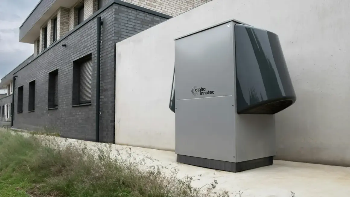Une pompe à chaleur Alpha Innotec est installée près d'un bâtiment moderne. Elle fonctionne pour réguler la température, mais combien de temps tourne une pompe à chaleur par jour ?