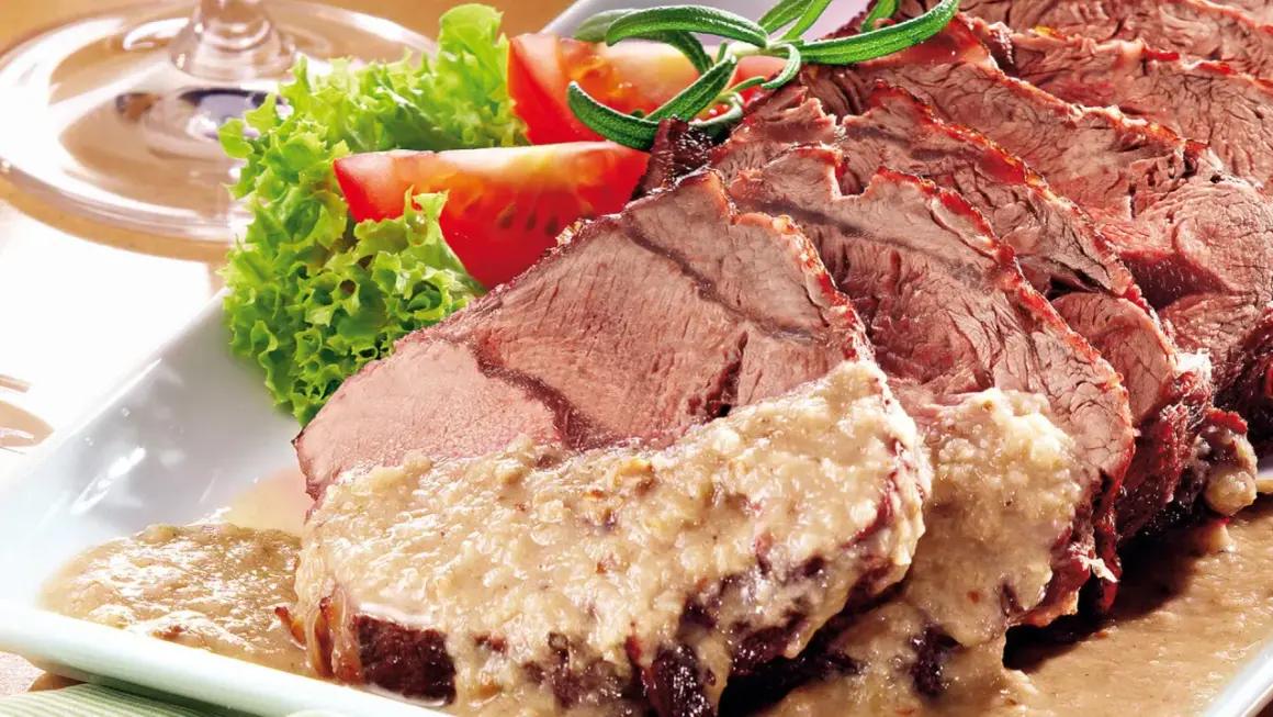 Saftiger Sauerbraten, in Scheiben geschnitten, mit cremiger Sauce und Beilagen. Perfekt für ein langes Schmoren, damit 1 kg Sauerbraten zart wird.