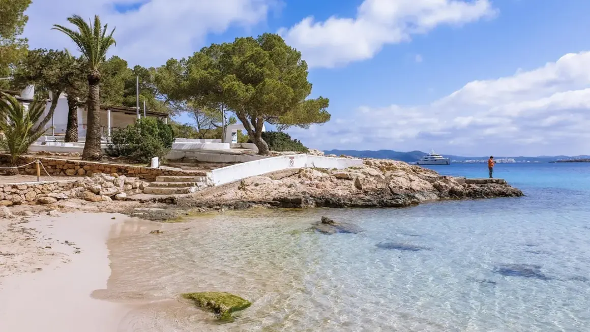 Piękna plaża na Ibizie, idealne miejsce, by zobaczyć błękitne morze i poczuć słońce. Na horyzoncie luksusowy jacht.