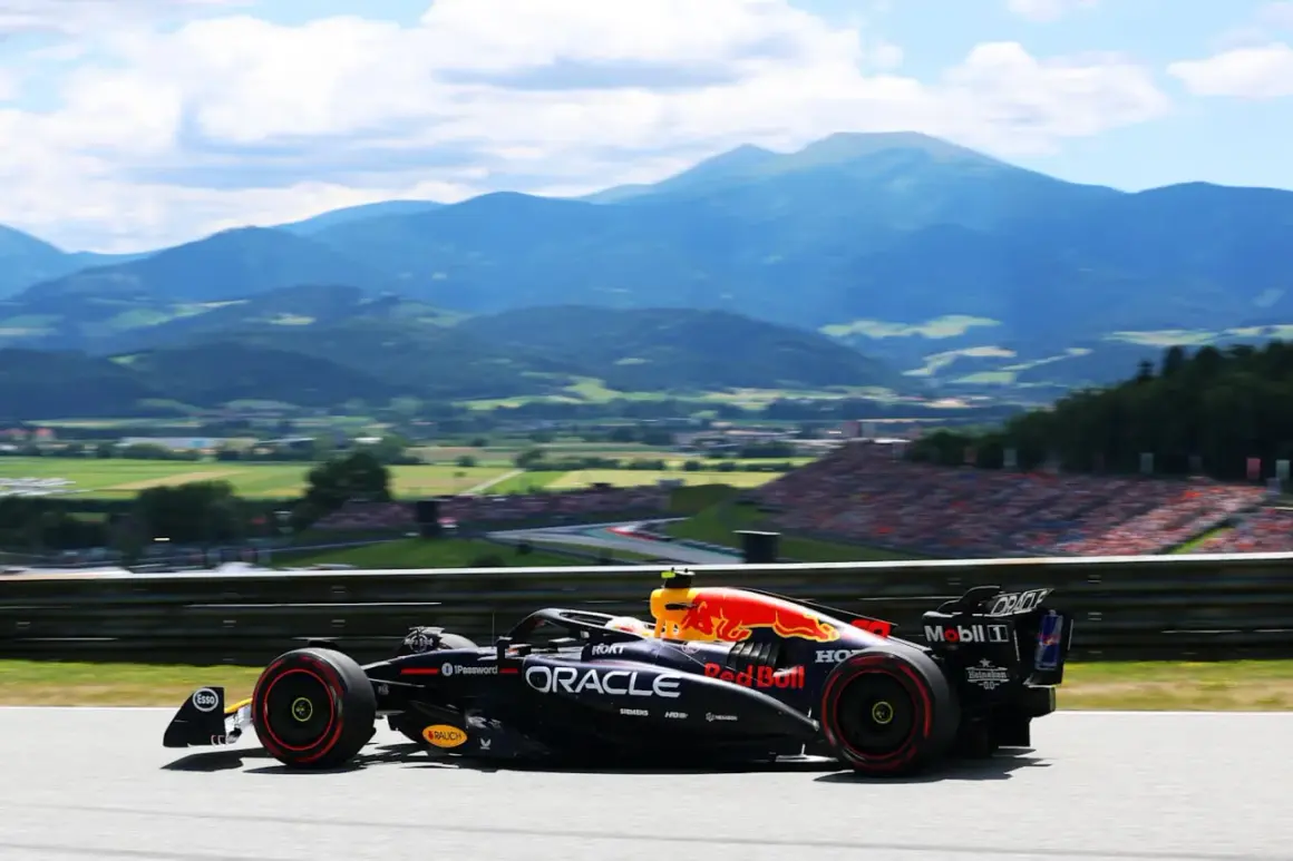 Un coche de Red Bull compite en el Gran Premio de Austria, con montañas y público al fondo.