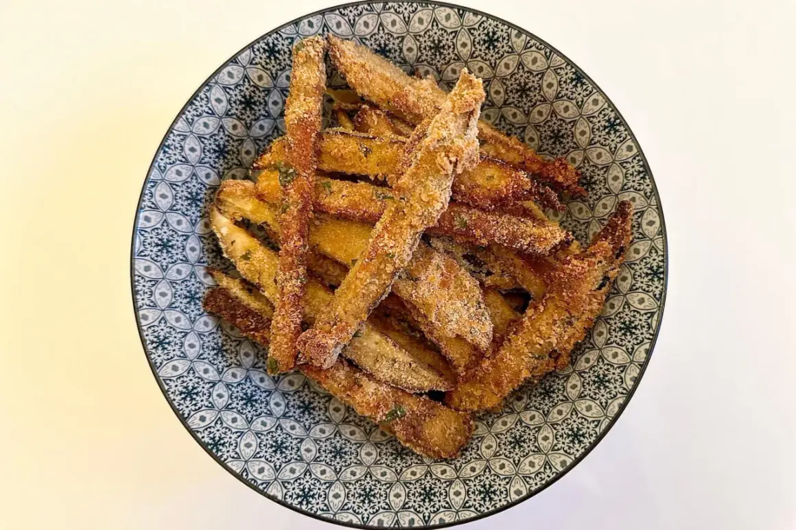 Bastoncini di melanzane impanate, un classico delle ricette della nonna, serviti in una ciotola decorata.