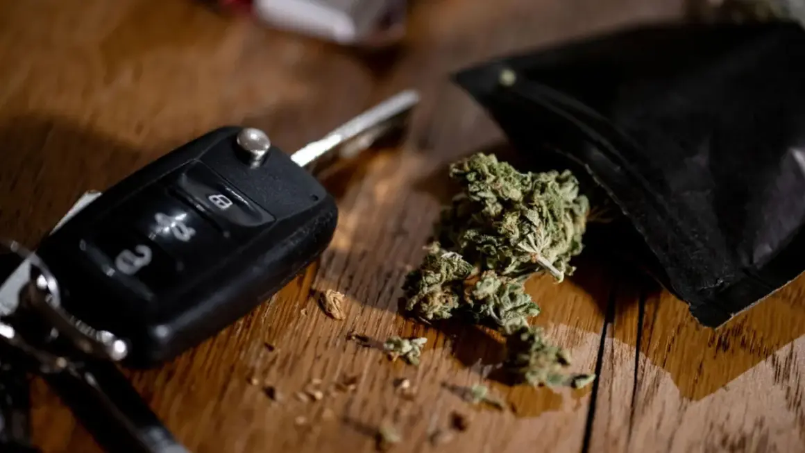 Autoschlüssel und Cannabis auf Holztisch. Ein gefährlicher Gedanke: Cannabis am Steuer.