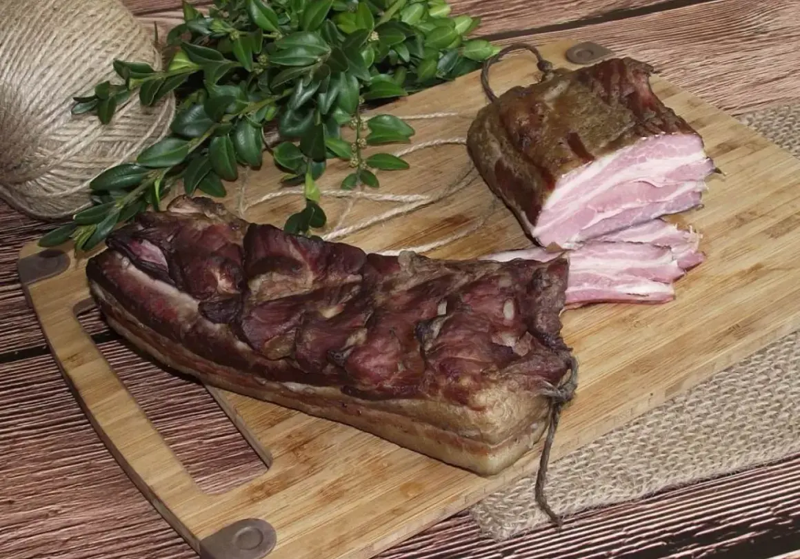 Dwa kawałki wędzonego boczku na desce. Zastanawiasz się, czym natrzeć boczek do wędzenia? Ten wygląda apetycznie!
