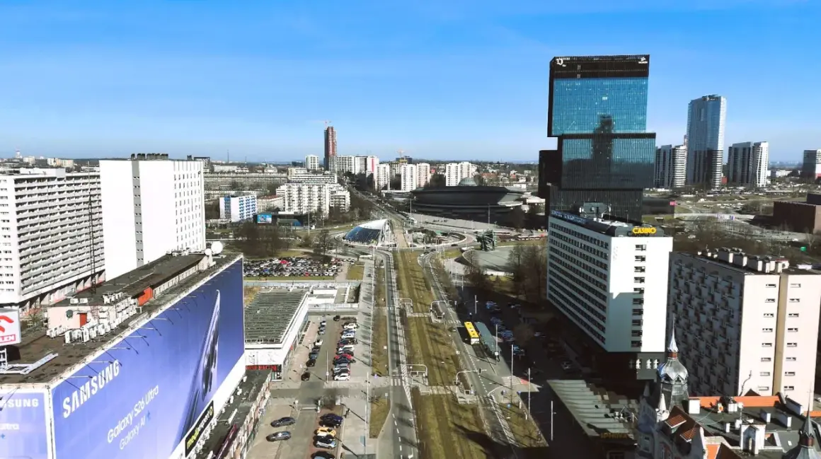 Widok na nowoczesne centrum Katowic z wieżowcami i drogą w tle.