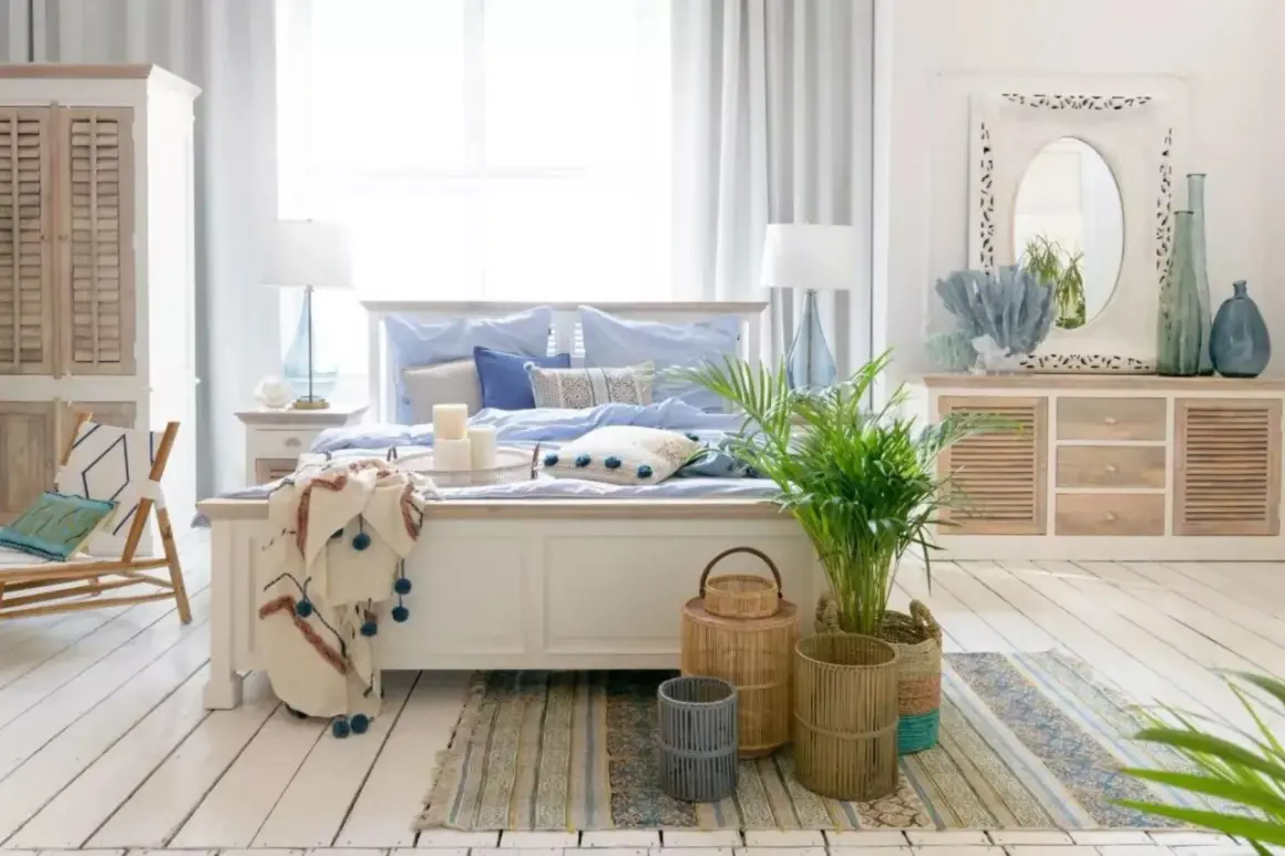 Sypialnia w stylu hamptons z jasnym łóżkiem, niebieską pościelą, wiklinowymi koszami i roślinami.