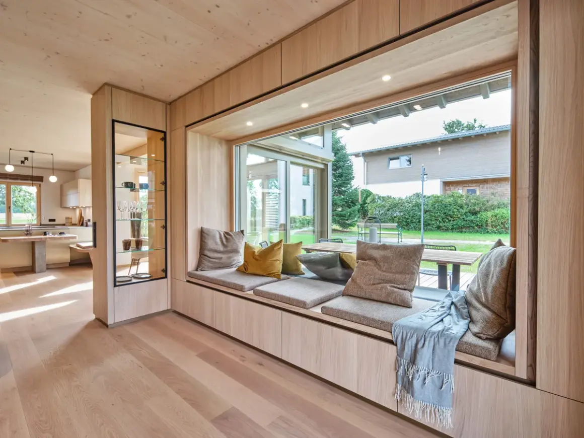 Gemütliche **Ideen für Sitzfenster**: Ein einladender Bereich mit Kissen und Decke lädt zum Verweilen ein, während der Blick ins Grüne schweift.
