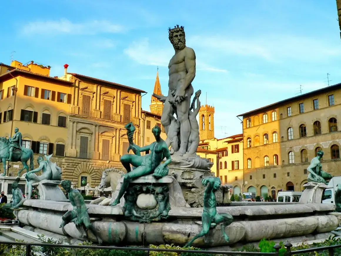 La Fontana del Nettuno a Firenze, con le sue sculture in bronzo e marmo, domina la piazza sotto un cielo azzurro.