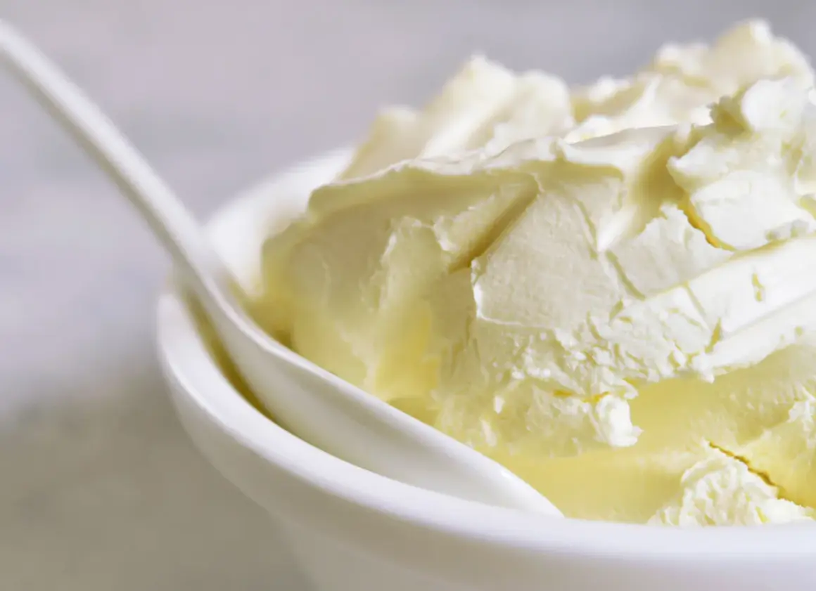 Kremowa masa w białej miseczce z łyżką. Szukasz, czym zastąpić mascarpone? Oto puszysta alternatywa.